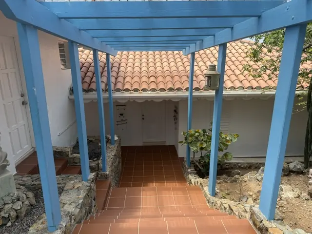 Covered blue walkway and terracotta path beside Coralita guest room entrances.