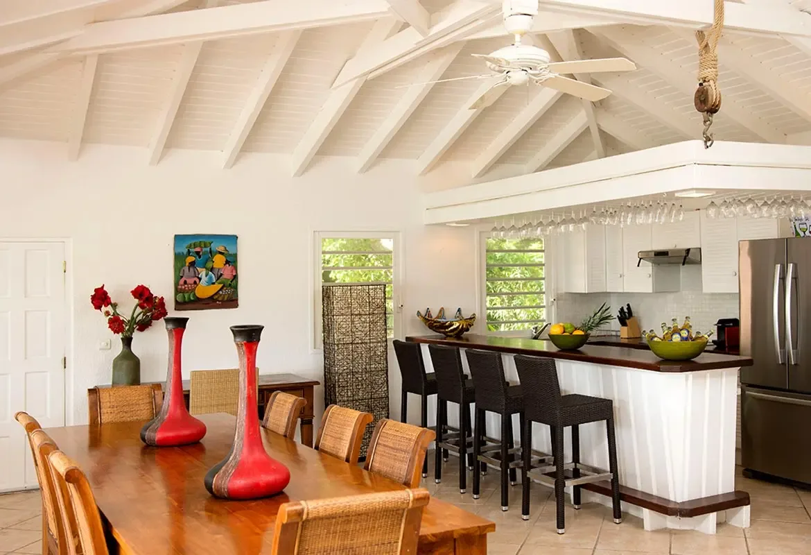 Open-concept dining and kitchen with vaulted ceiling — the large wooden table meets a modern breakfast bar.