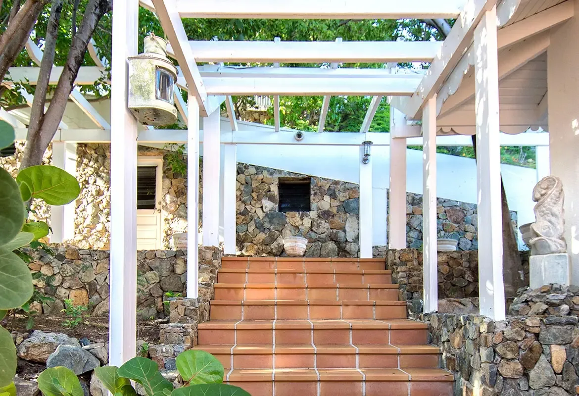Ascending stairs with white trellis and stone walls — architectural elegance meets tropical lushness at the entrance.