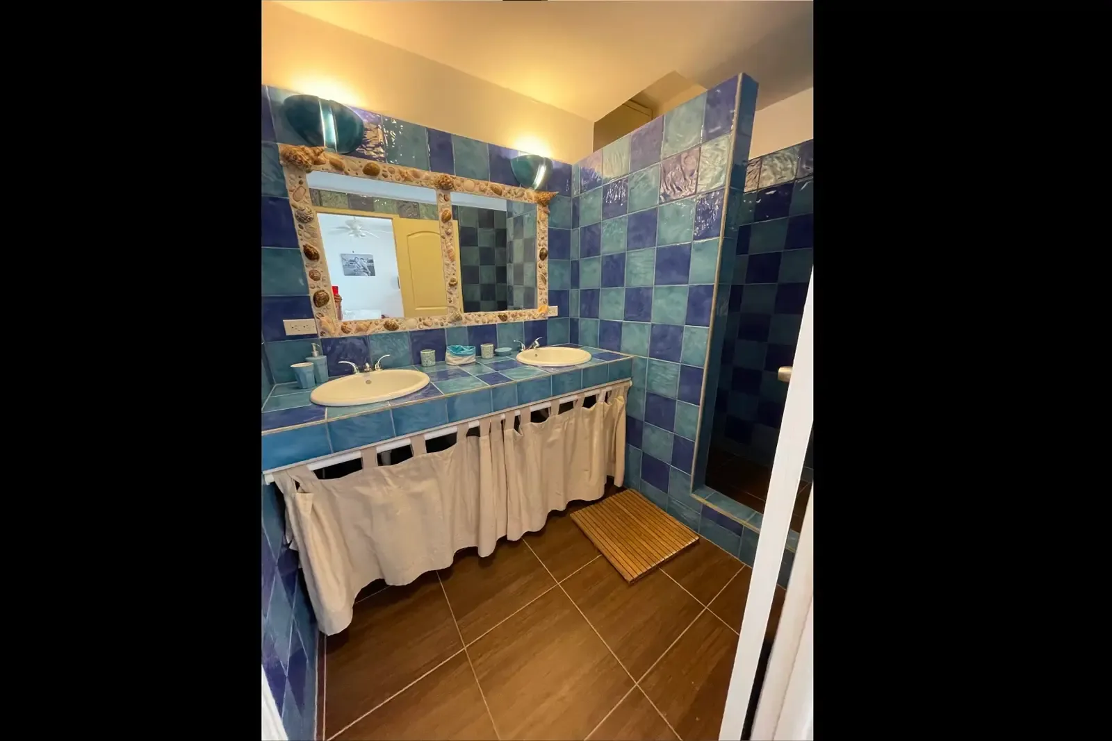 Turquoise tiles and shell-framed mirror — a bathroom that feels like the sea.