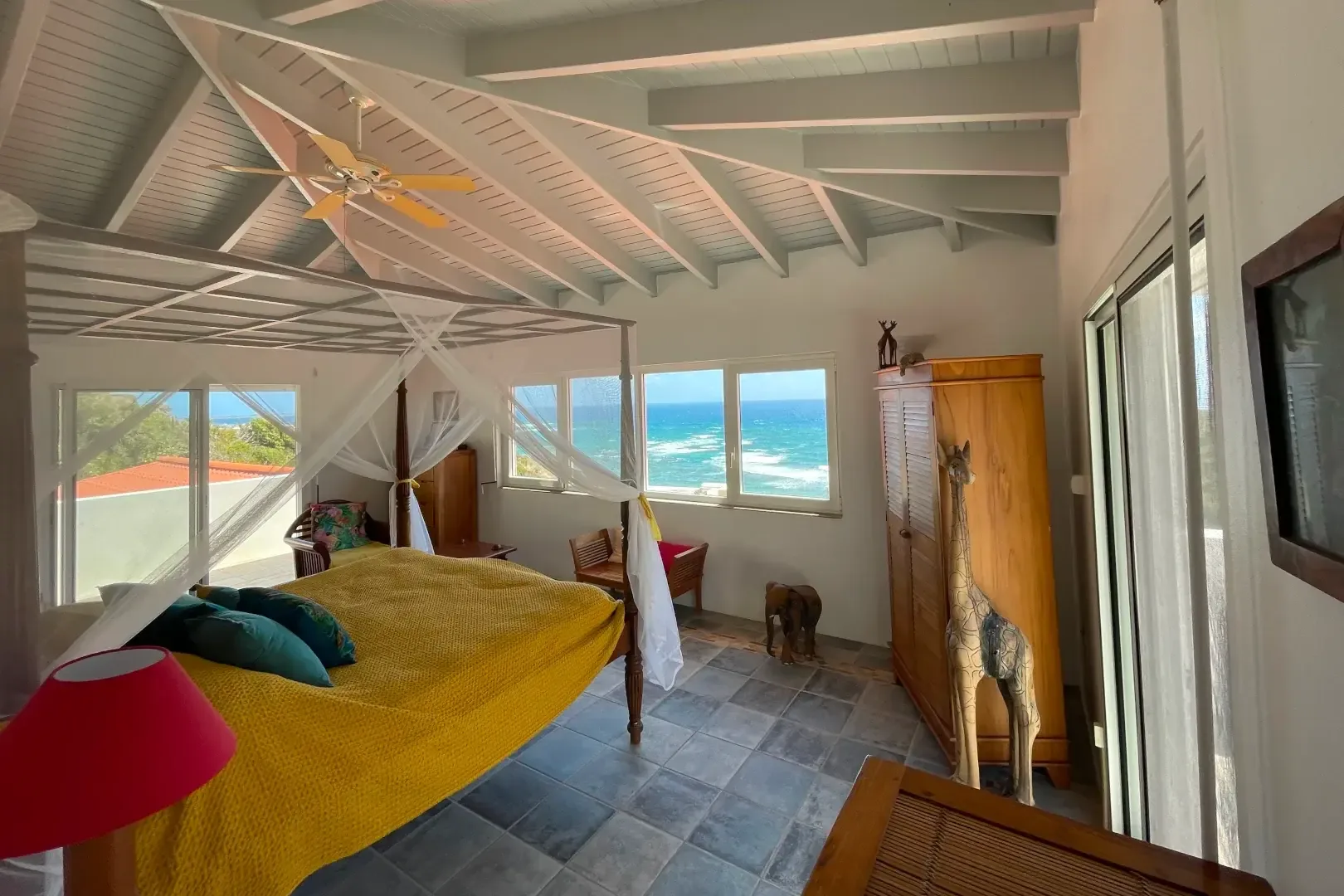 A white canopy bed with direct ocean views — fall asleep to the sound of waves.