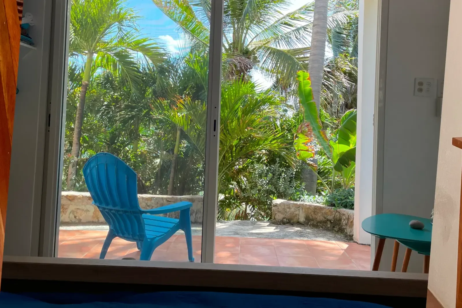 A bedroom view to the tropical patio — lush palms frame your morning.