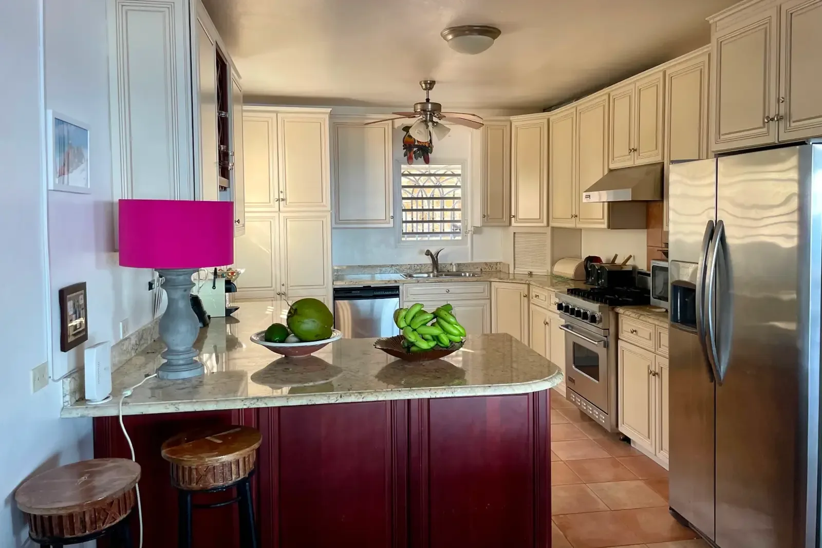 A chef's kitchen with pink pendant light and fresh island fruit — cook with Caribbean inspiration.