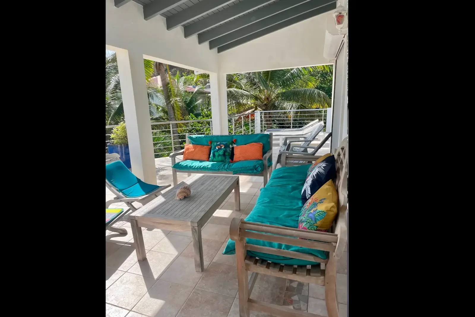 Covered patio with teal cushions — escape the sun in island style.
