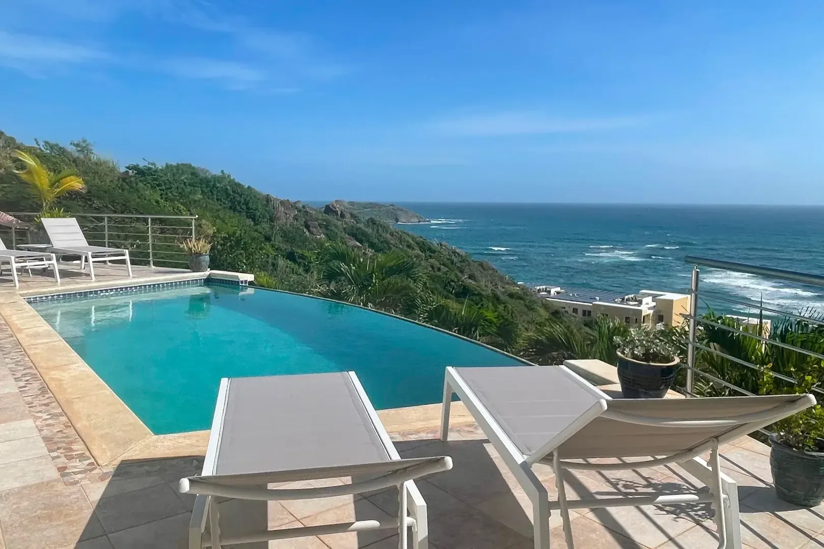 Your infinity pool deck with white loungers — where the ocean stretches to the horizon.