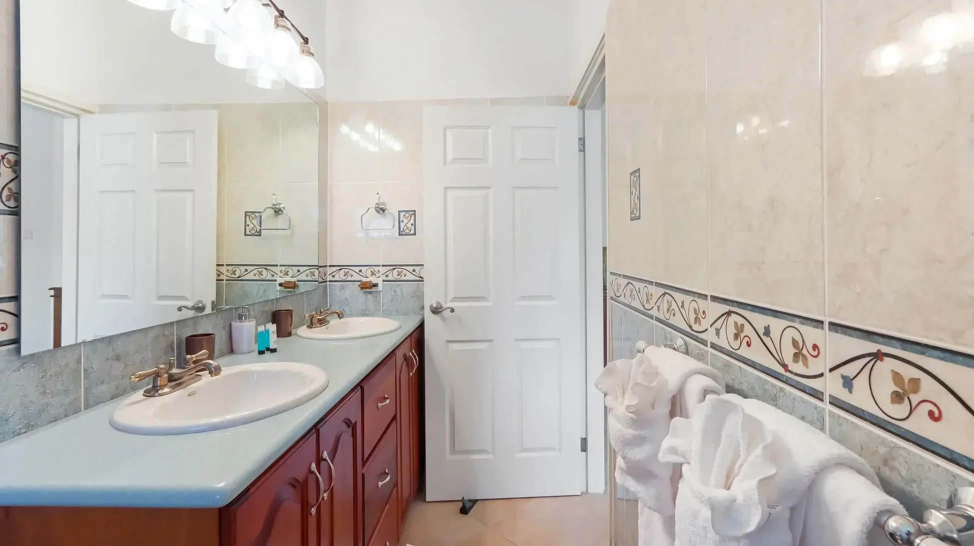 Double vanity with light blue granite counter and brass faucets. The large mirror and vanity lighting create a bright, inviting space.