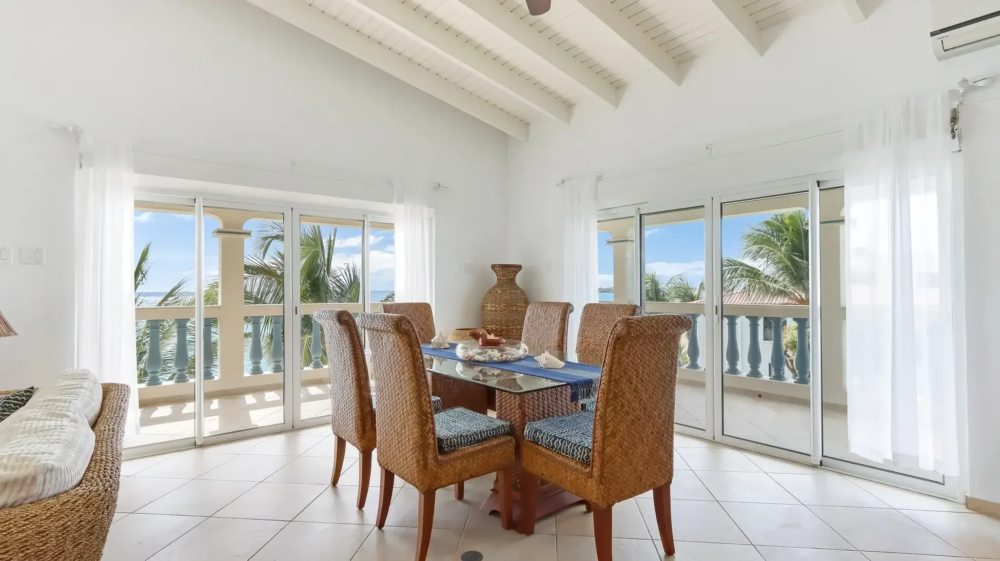 Dine with ocean views at a glass table with seashell centerpiece, six wicker chairs, and vaulted ceilings. Sliding doors bring the Caribbean right to your table.