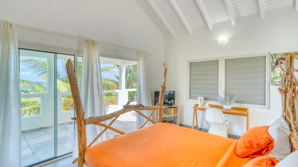 Bedroom with orange linens, desk area, and sliding glass doors