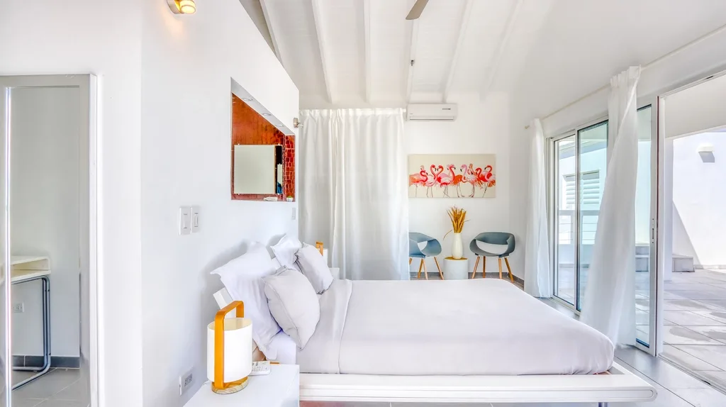 Bedroom with white linens, sitting area, and terrace access