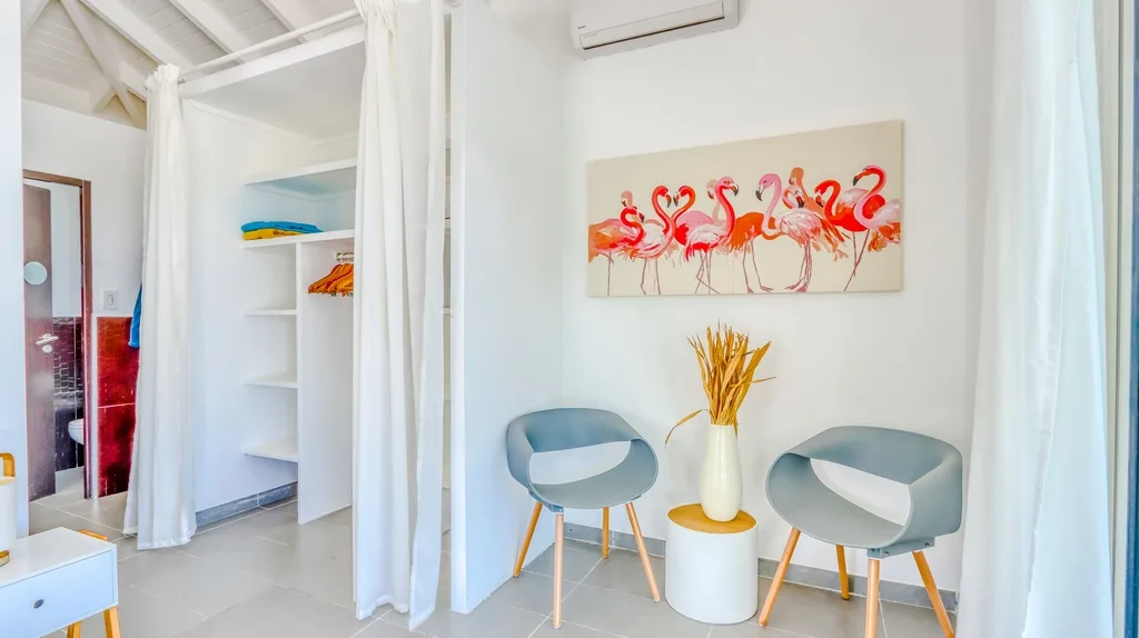 Bedroom seating corner with white drapery and coral artwork