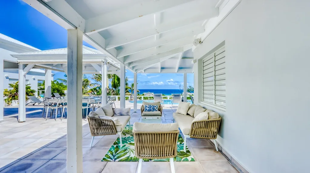 Covered terrace lounge with woven chairs and open pool view