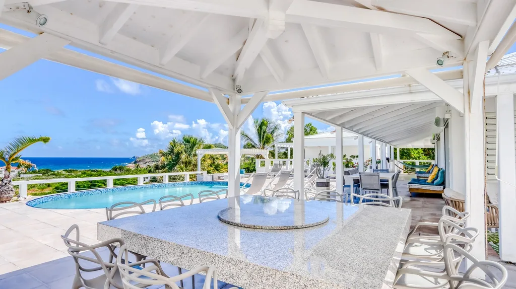 Covered outdoor dining area with round granite table and ocean view