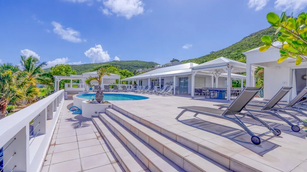 Pool terrace with sun loungers and hillside backdrop