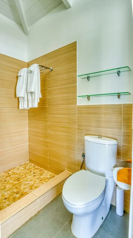 Compact bathroom with pedestal sink and pebble-style shower floor