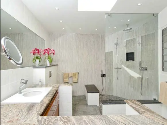 A spa-like shower with natural light from above — granite finishes and a built-in bench invite long, relaxing rinses.