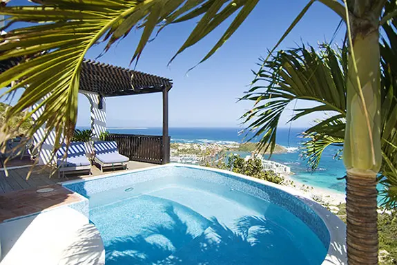 A curved pool, wooden deck, and that view — your private terrace with the Caribbean at your feet.