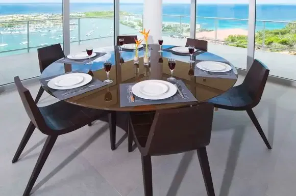 Six modern chairs surround the elegant glass-top dining table, perfectly positioned against floor-to-ceiling windows that frame the spectacular marina and ocean panorama.                                                                                                                                                                                                                                                                                                                                                  +
 