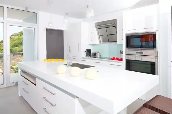 A pristine all-white kitchen features a generous central island, professional stainless steel appliances, and minimalist design that embodies modern luxury.                                                                                                                                                                                                                                                                                                                                                              +
 