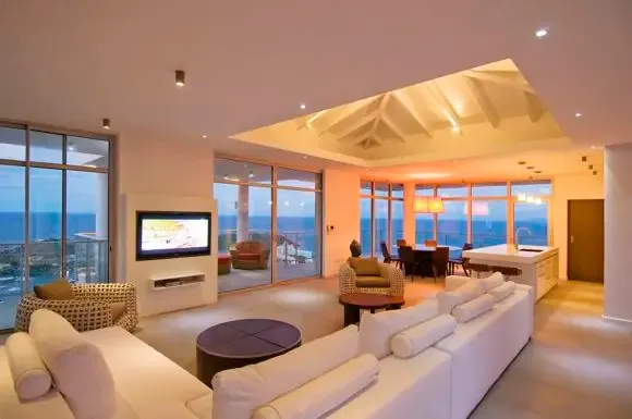 As twilight paints the sky, the open living, dining, and kitchen spaces glow with warmth beneath vaulted ceilings, all framed by panoramic ocean views.                                                                                                                                                                                                                                                                                                                                                                     +
 