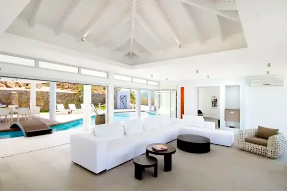 Floor-to-ceiling glass doors connect the vaulted living room to the terrace and private pool, where a wooden bridge and mountain views create a seamless indoor-outdoor experience.                                                                                                                                                                                                                                                                                                                                         +
 