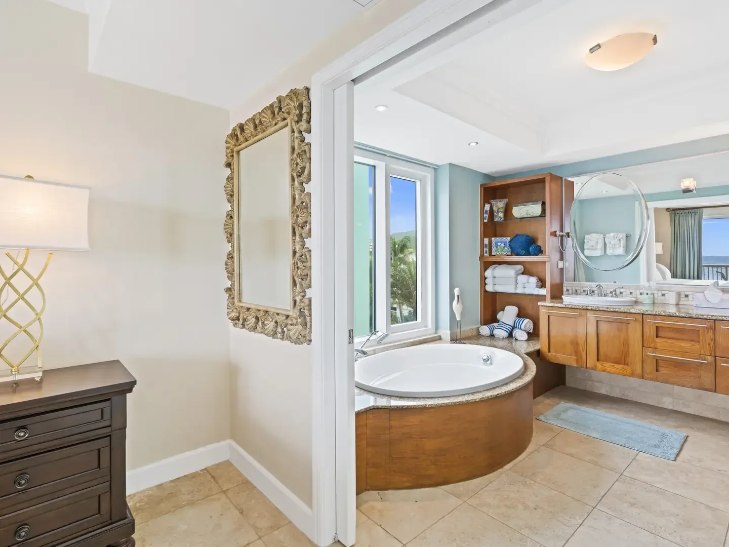Luxurious bedroom and bathroom suite with a jetted tub, wooden vanity, and scenic outdoor view