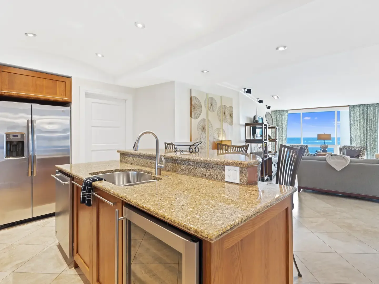 Modern villa kitchen and living room with ocean view, granite countertops, stainless steel appliances, and open-concept layout
