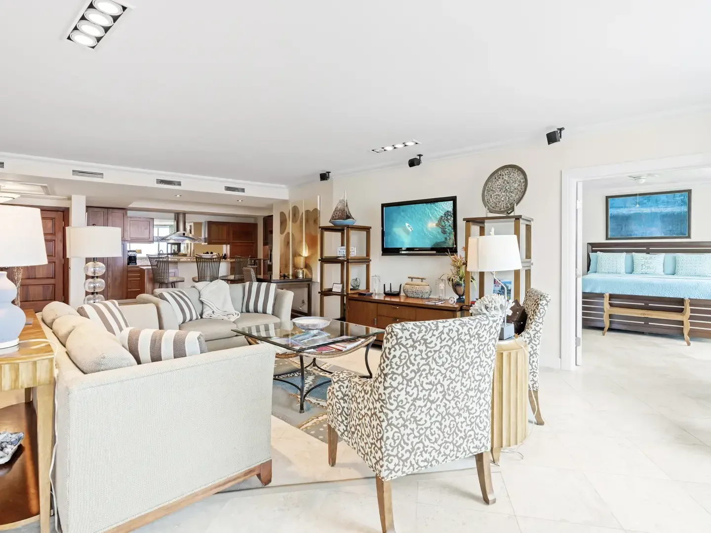 Spacious open-concept villa living room, kitchen, and bedroom with neutral furniture, blue accents, and modern lighting