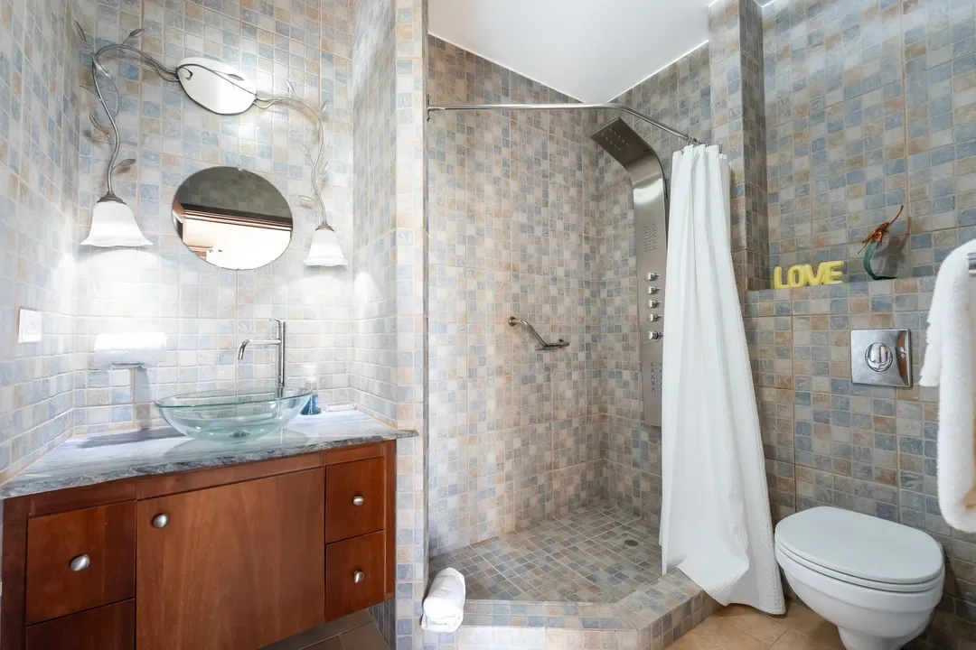 A spa-inspired bathroom — glass vessel sink, walk-in mosaic shower, and decorative touches that make every morning feel like luxury.