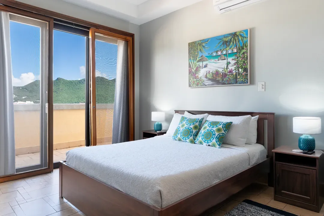 Coastal elegance at its finest — decorative pillows, turquoise lamps, and a tropical painting that echoes the island outside.