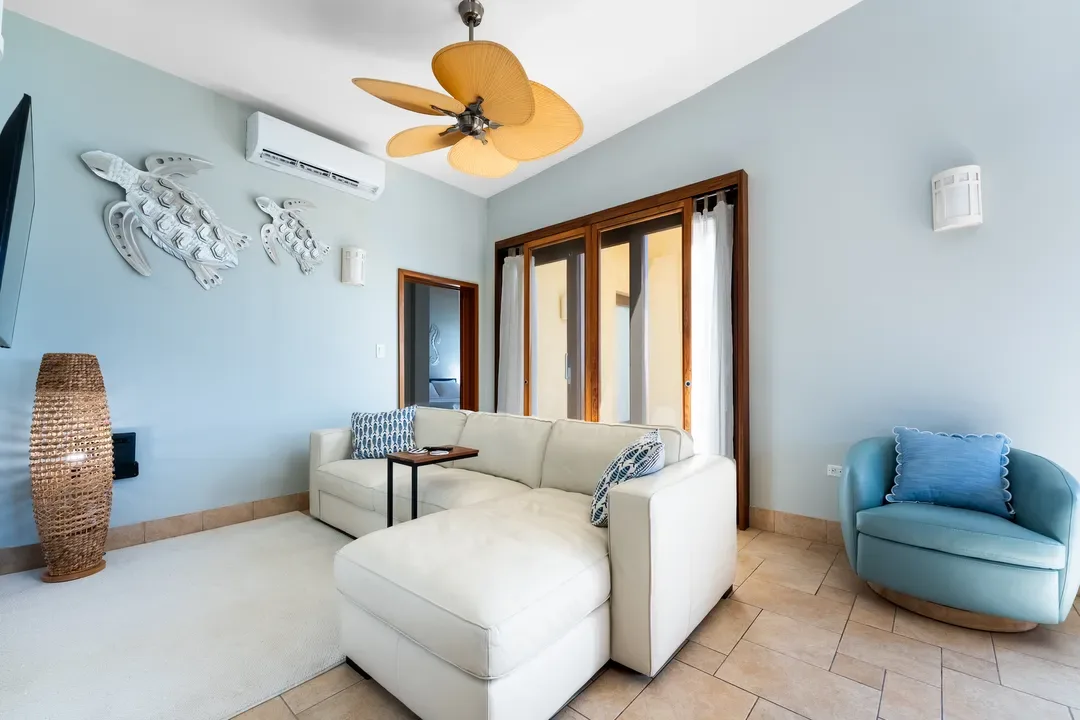 Unwind in your spacious living room — plush sectional, sea turtle art, and sliding doors that blur the line between indoors and paradise.