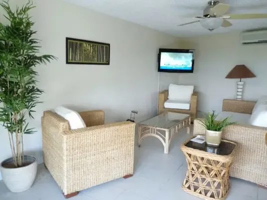 Bright indoor-outdoor living room with wicker seating and a relaxed Caribbean villa feel.