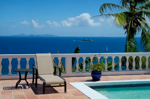 Ocean-view pool deck with terracotta terrace and sweeping Caribbean blue water beyond.