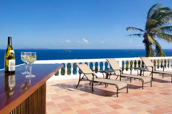 Ocean-view terrace with lounge seating and bar setup for sunset drinks.