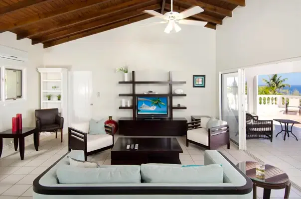 Vaulted living room opening to the terrace with wide ocean views and a breezy island atmosphere.