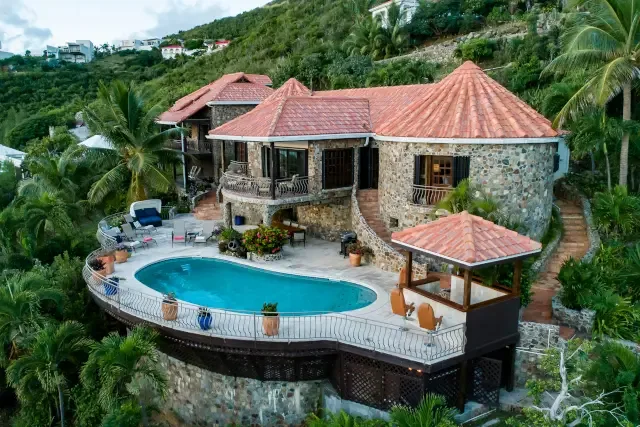 An aerial view of your exclusive retreat — the stone villa nestled in vibrant tropical greenery.