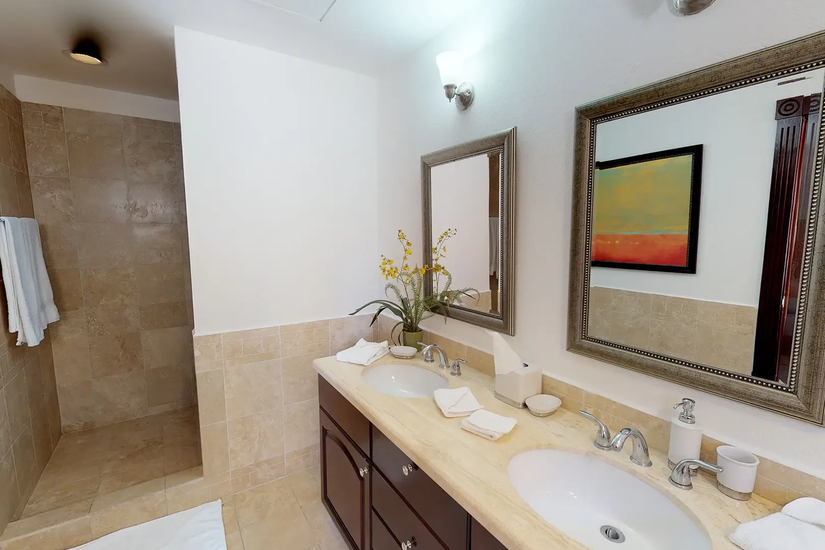Double vanity with marble countertop, two sinks, mirrors, and walk-in tiled shower.