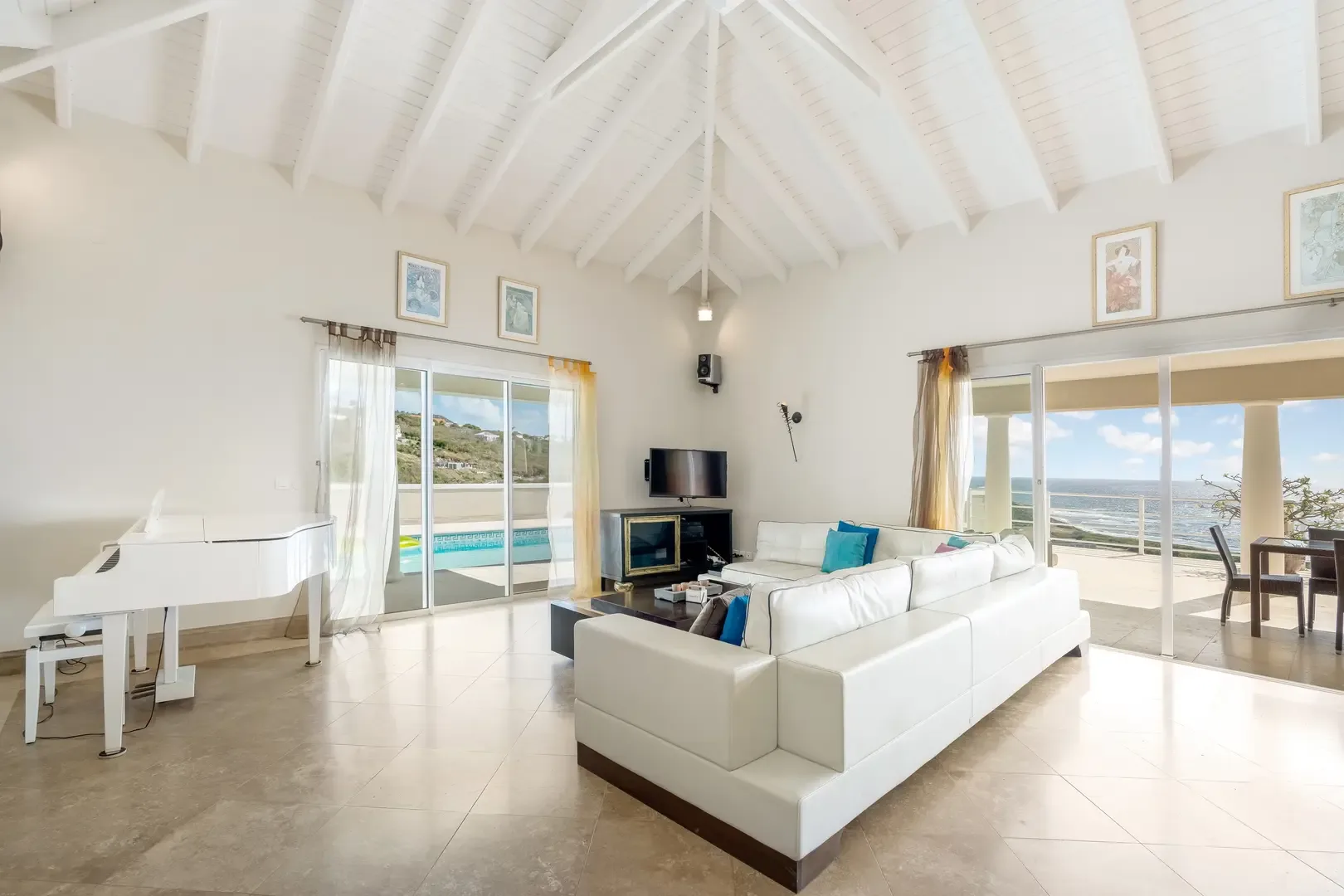 A white grand piano anchors the space — elegant living meets Caribbean ease.
