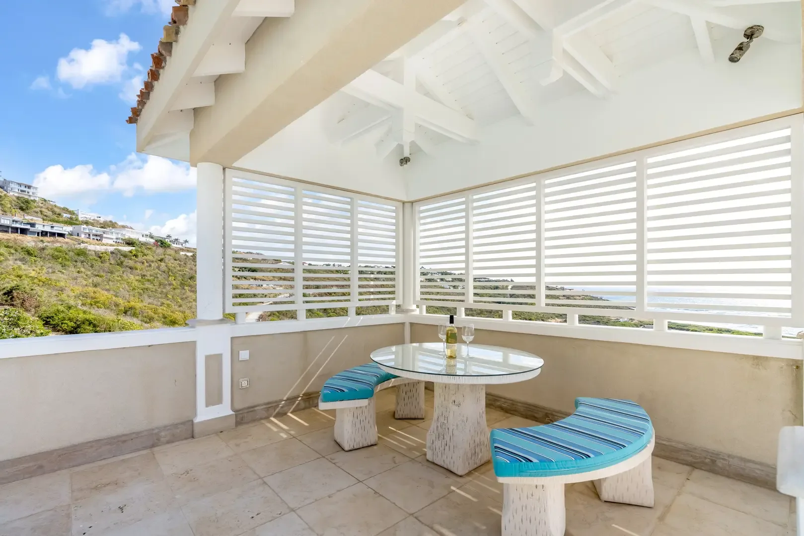 The covered terrace stretches wide — ocean views from your dining table.