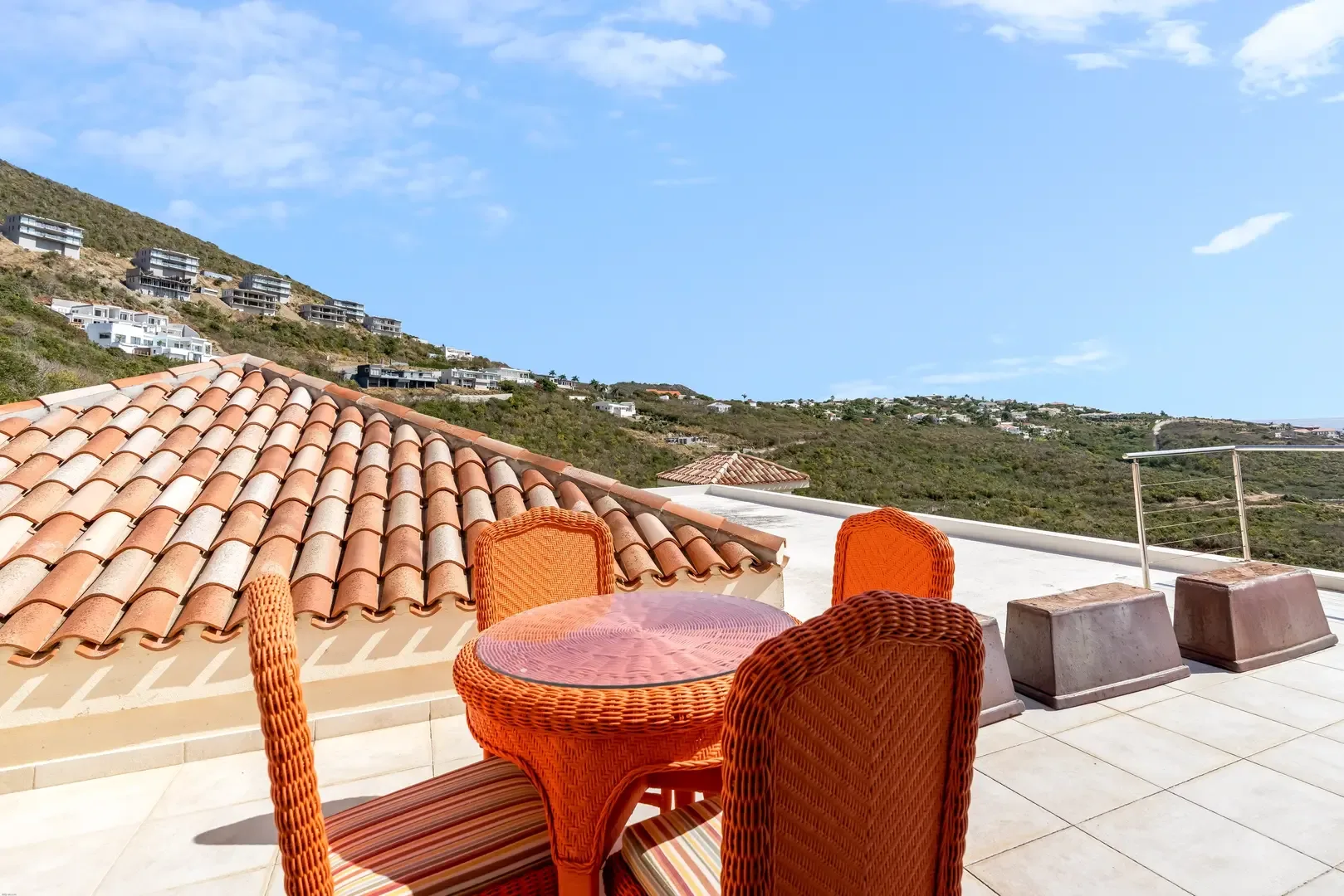 Outdoor terrace with wicker furniture — hillside and ocean views.