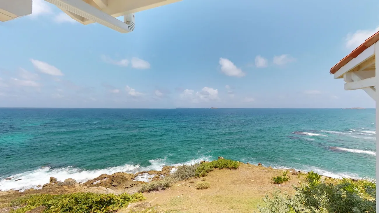 Ocean view from Timeless Tides villa showcasing turquoise waters, rocky coastline, and clear blue sky