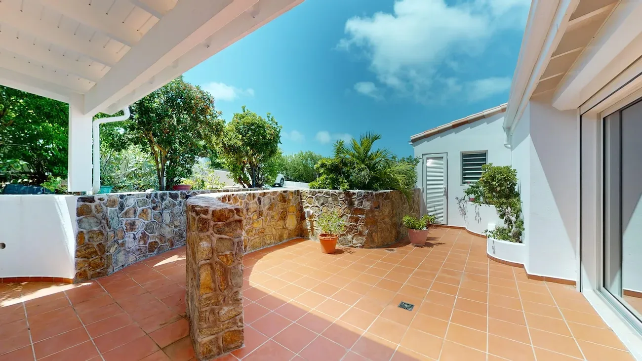 Covered patio with terracotta tiles and stone walls at Timeless Tides.