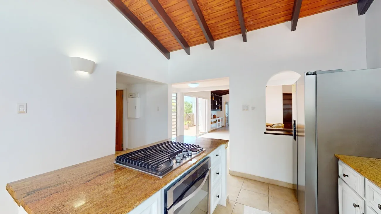 Kitchen with granite island, gas cooktop and wood ceiling.
