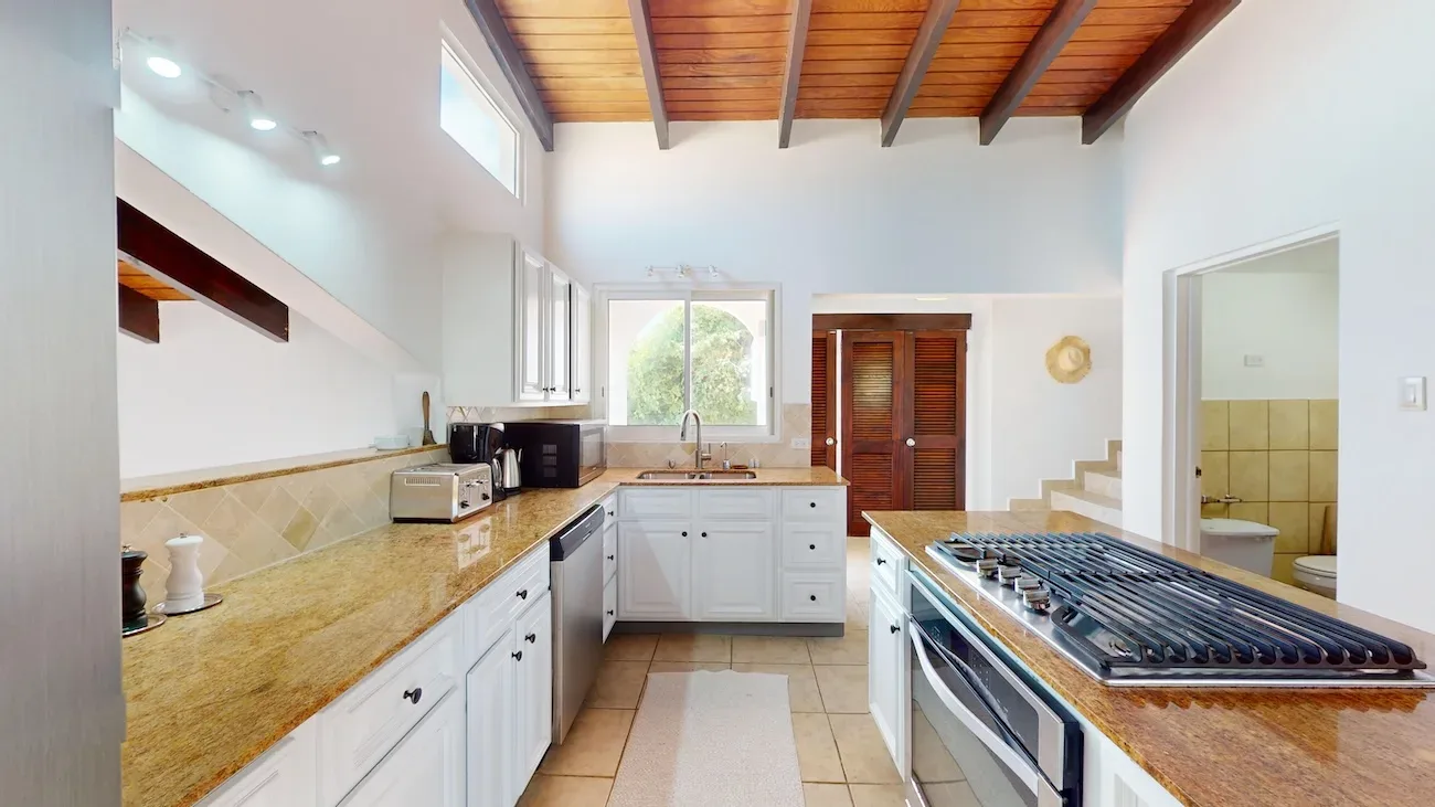 Bright kitchen with white cabinets, island and wood beam ceiling.