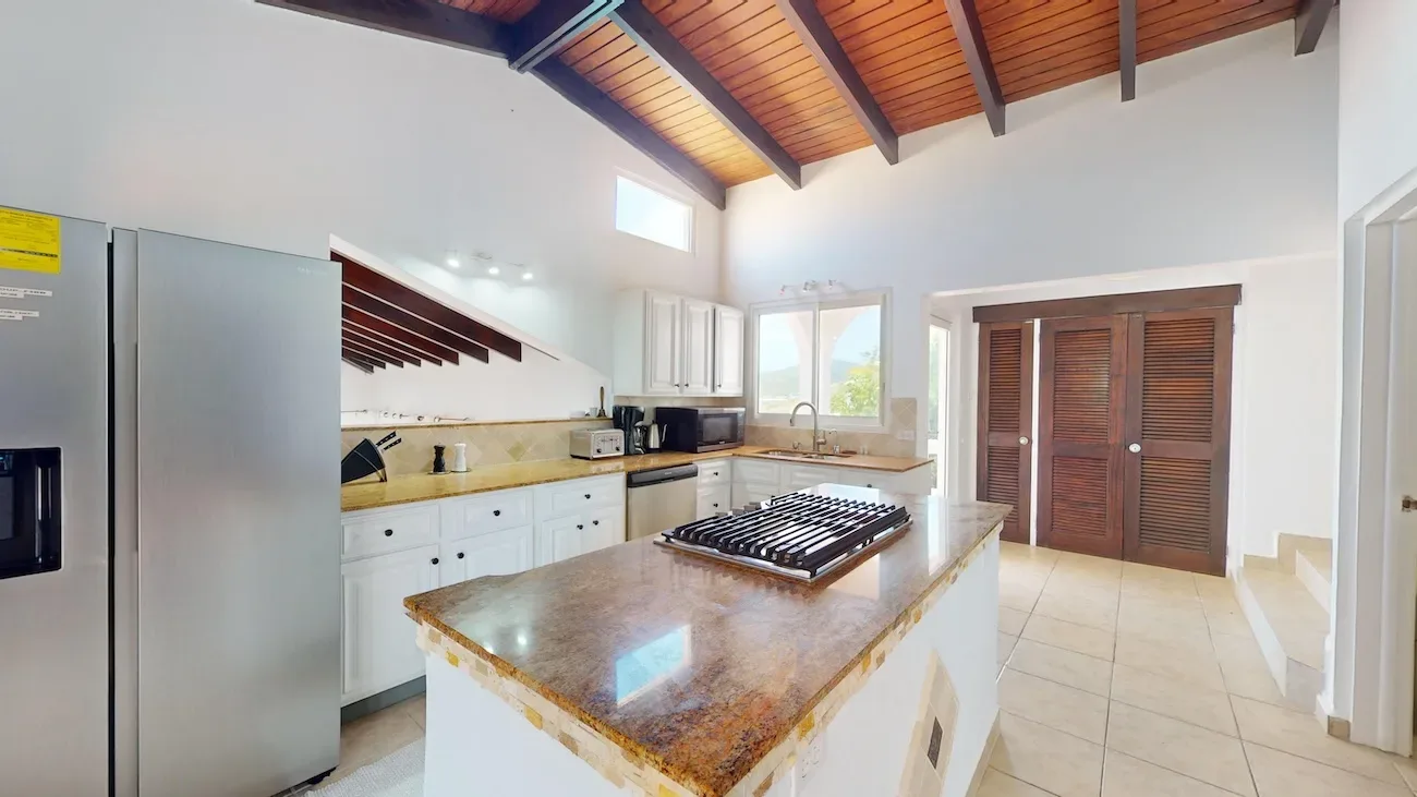 Bright kitchen with vaulted wood ceiling, white cabinets and island.