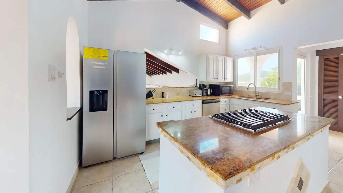 Modern kitchen with white cabinets, stainless steel fridge, granite island gas cooktop, and mountain view