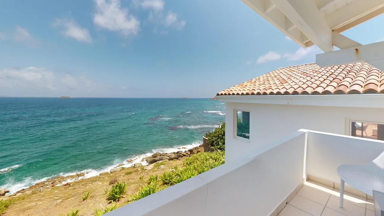 White villa terrace with terracotta roof and panoramic ocean view over turquoise sea and rocky coastline