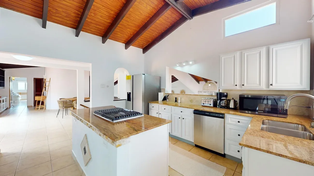 Kitchen with vaulted wood ceiling, island and white cabinets.