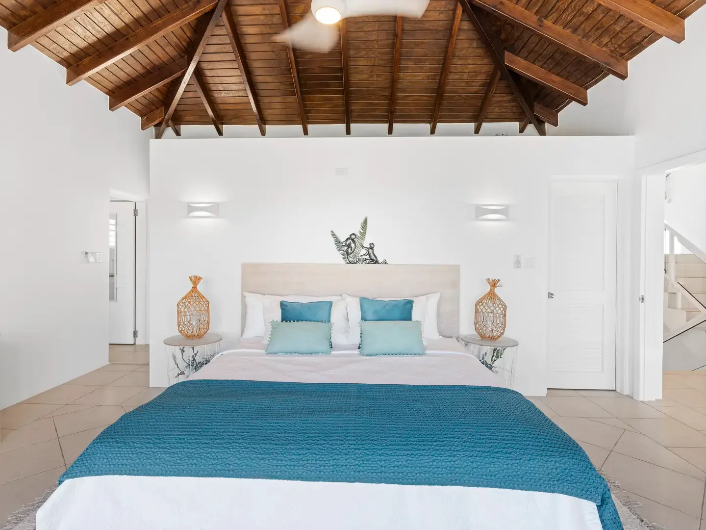 Unique pineapple lamps illuminate this charming bedroom, where island style meets restful comfort under vaulted ceilings.