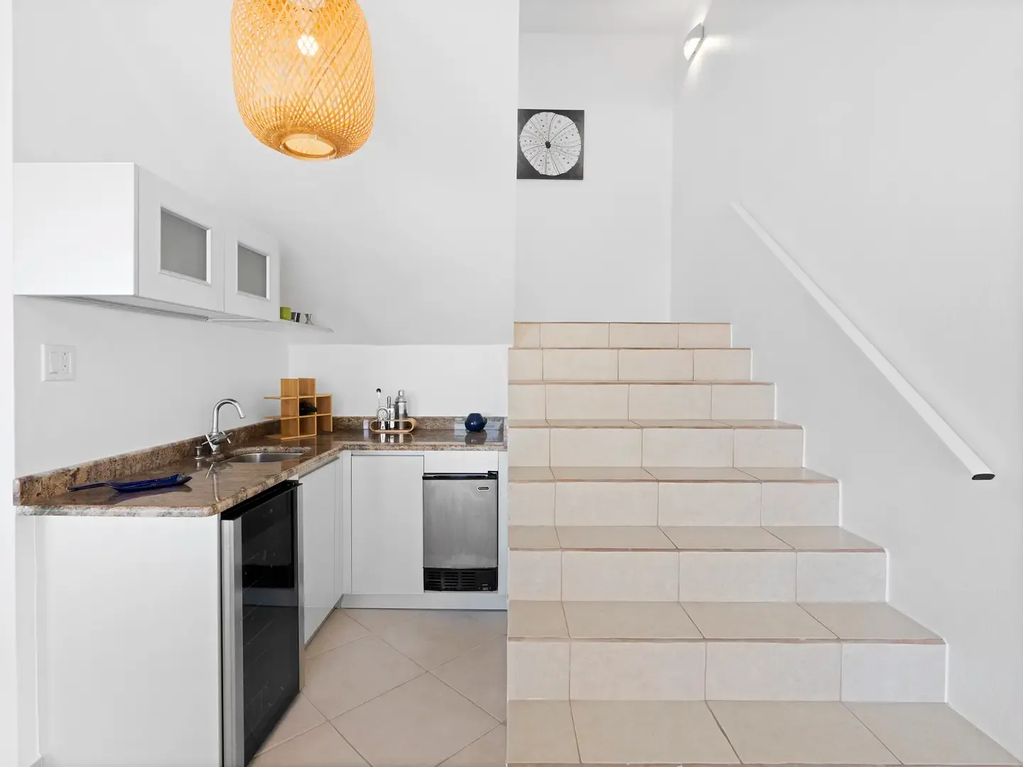 The heart of the home connects kitchen to upper levels, where woven pendant lights illuminate your culinary adventures.