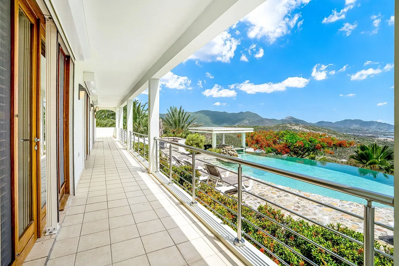 Covered villa terrace with infinity pool, mountain views, stainless steel railings, and tropical landscape
